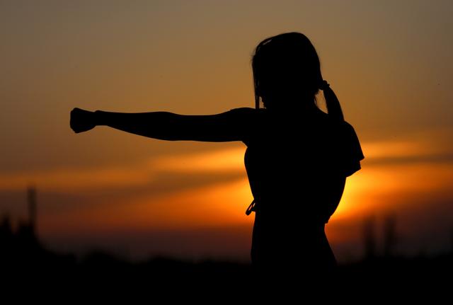A girl practicing martial arts in the sunset.